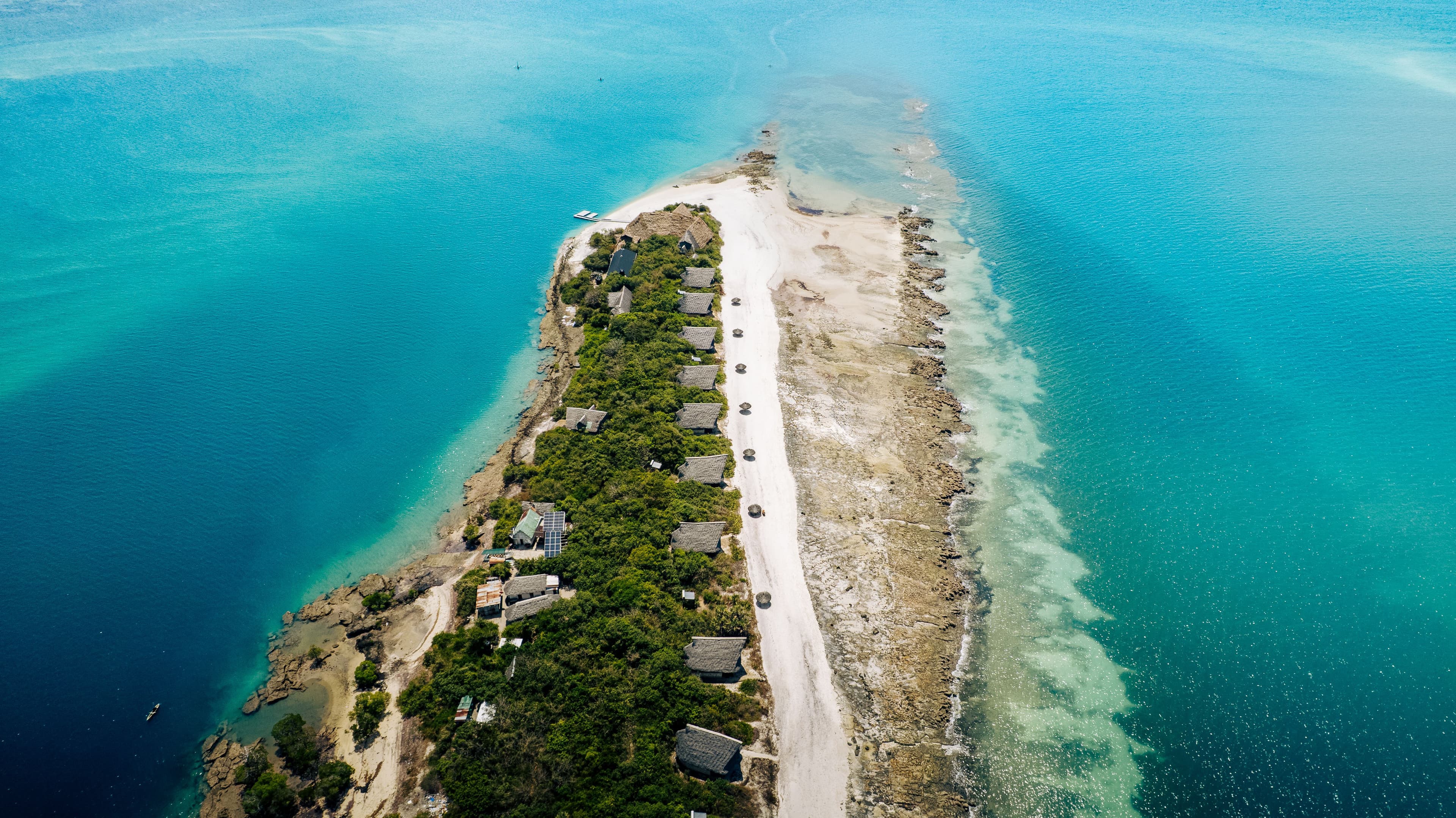 Aerial view of a thatched-roof island lodge on a narrow sandbank in the Bazaruto Archipelago