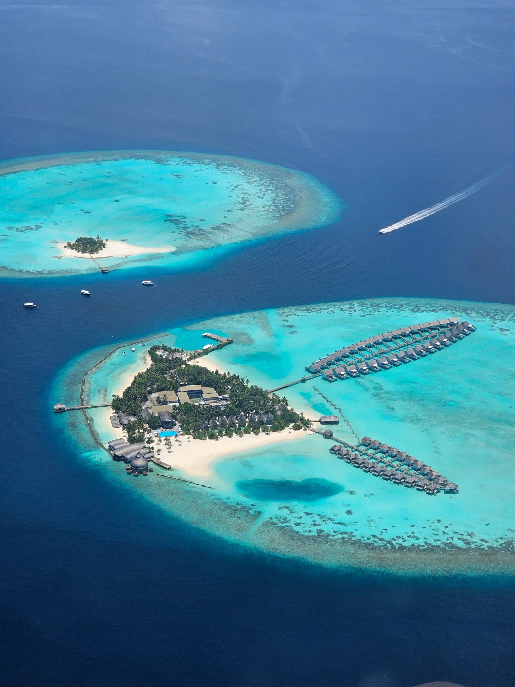 Aerial view of an island resort's overwater bungalows within a coral atoll
