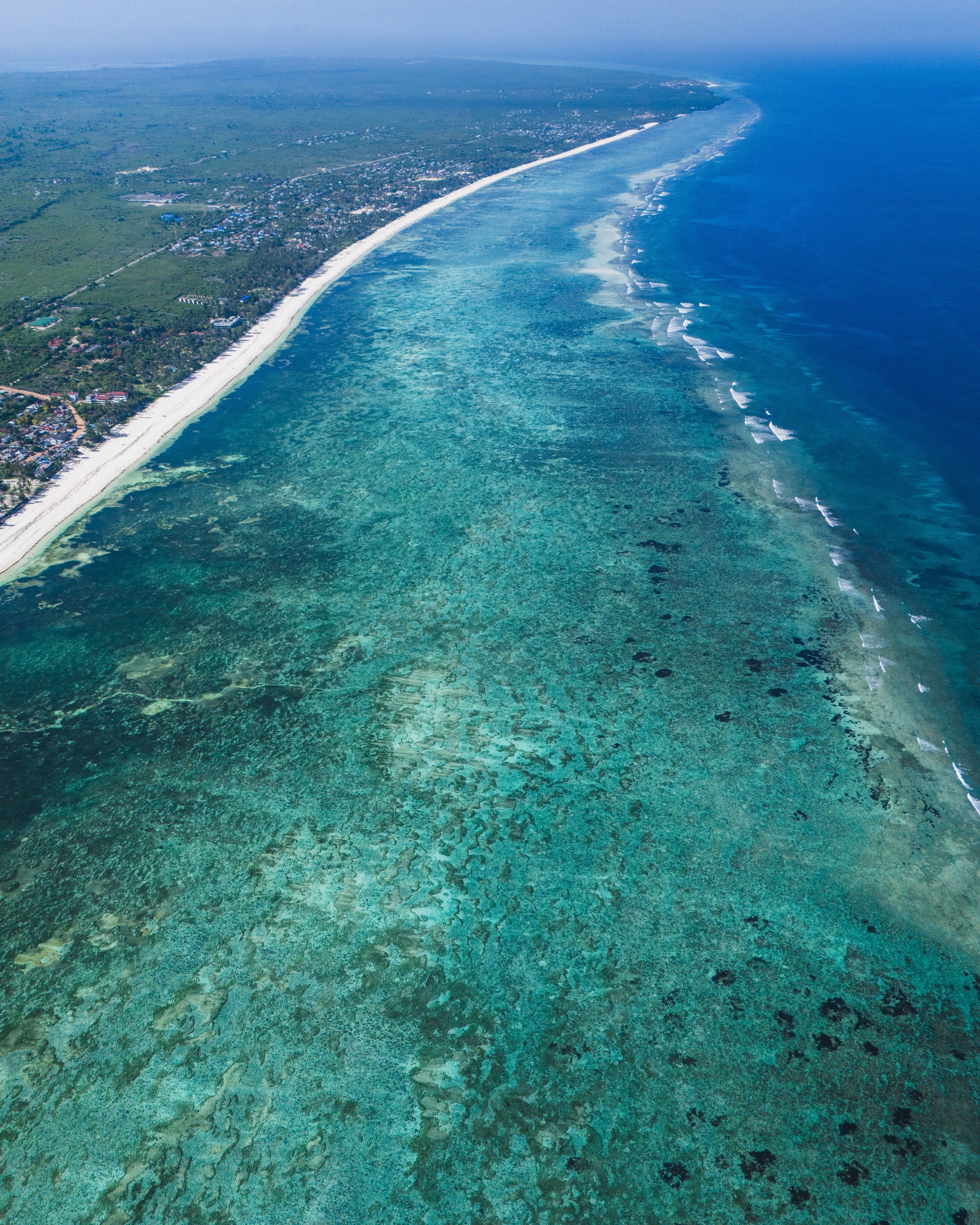Aerial view of a turquoise barrier reef along a white sand coastline