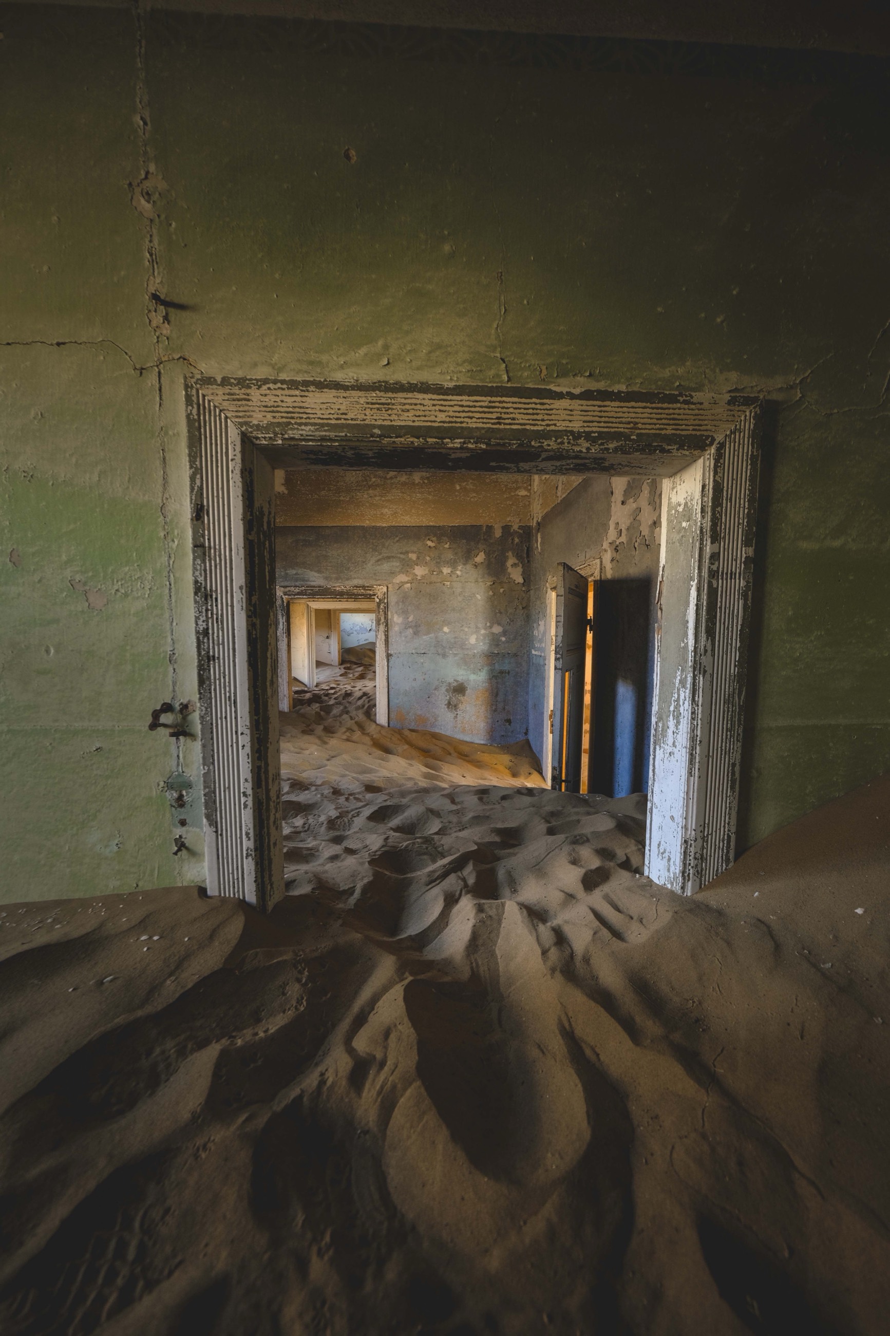 Sand drifting through the doorways of an abandoned Kolmanskop house