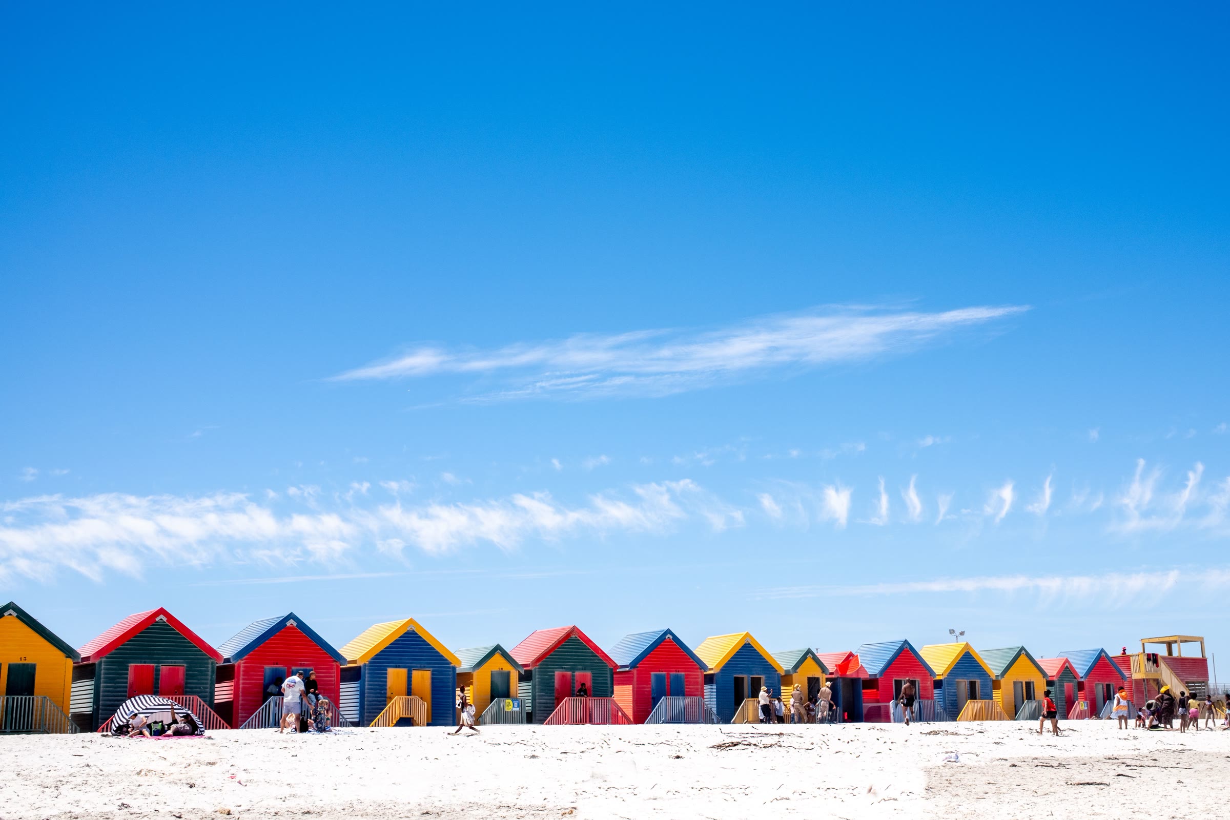 The brightly painted beach huts of Muizenberg under a clear blue sky